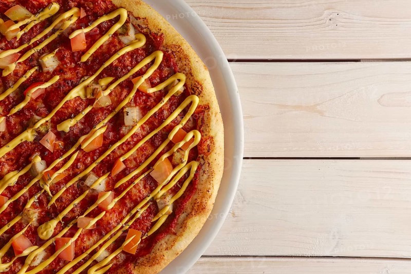 Top view of pizza with sun-dried tomatoes and mustard sauce