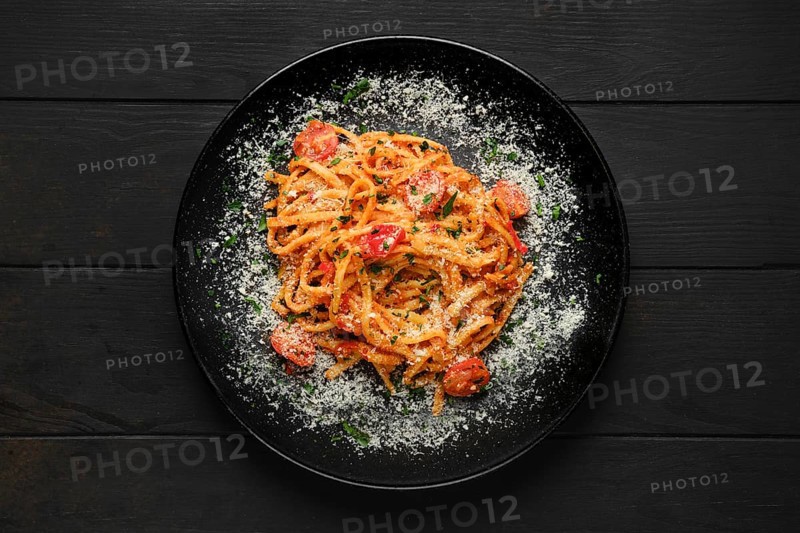 Top view of spaghetti with tomato cherry and grated parmesan on a plate