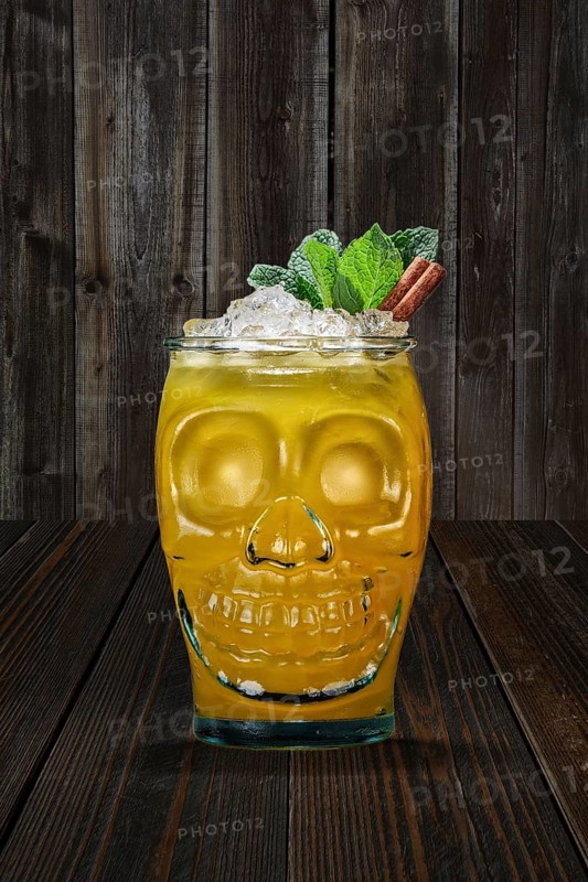 Halloween cocktail in goblet skull on wooden shelf. Jolly Roger drink in glass cup in the shape of skull