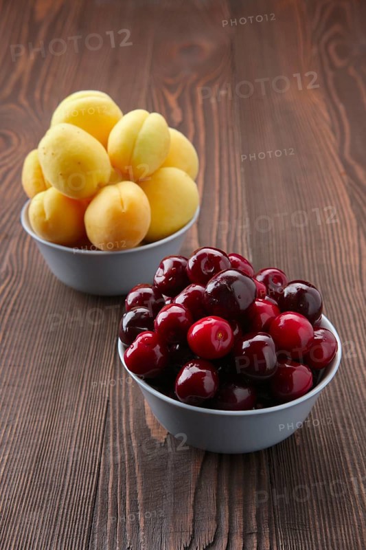 Cherries and apricots on dark wooden background