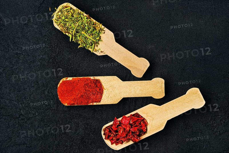 Set of spice in small wooden spoon on black concrete background
