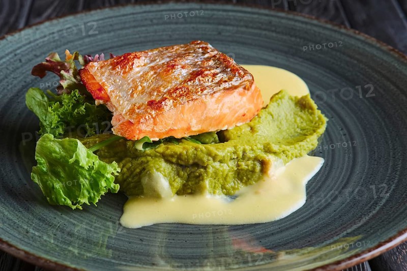 Fried salmon fillet with salad leaves and cream sauce decorated with caviar
