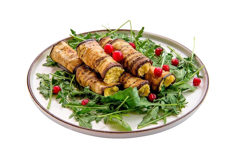 Eggplant rolls stuffed with soft cheese and garlic decorated with arugula and cranberry