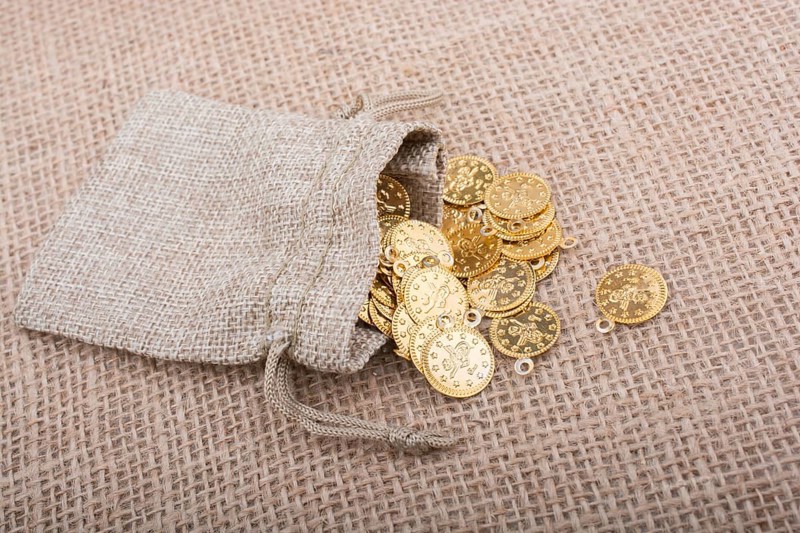 Fake gold coins out of a little sack on canvas