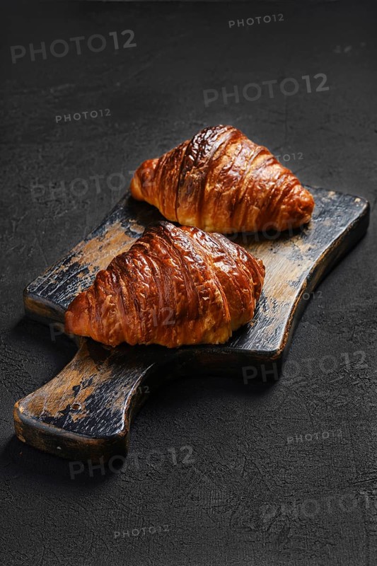 Crispy croissant on shabby wooden serving board