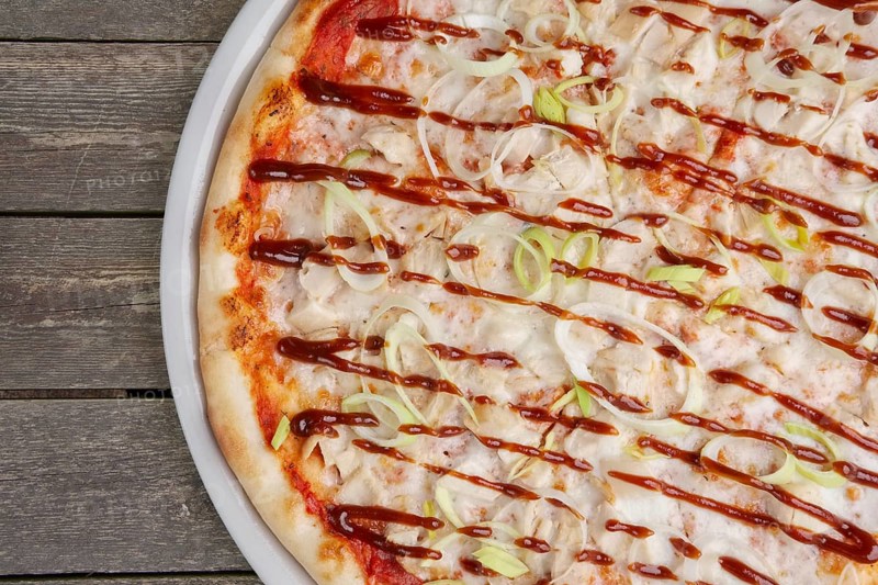 Top view of part of pizza with chicken barbecue on wooden table