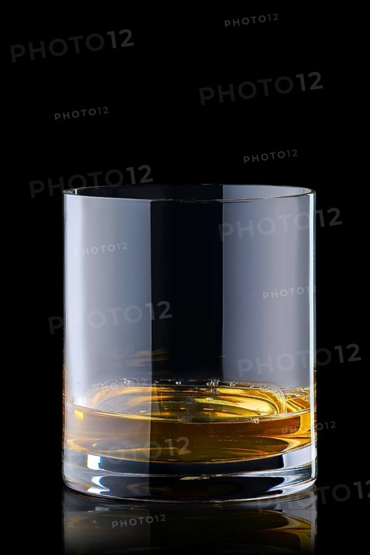 Portion of bourbon in transperent glass isolated on black background