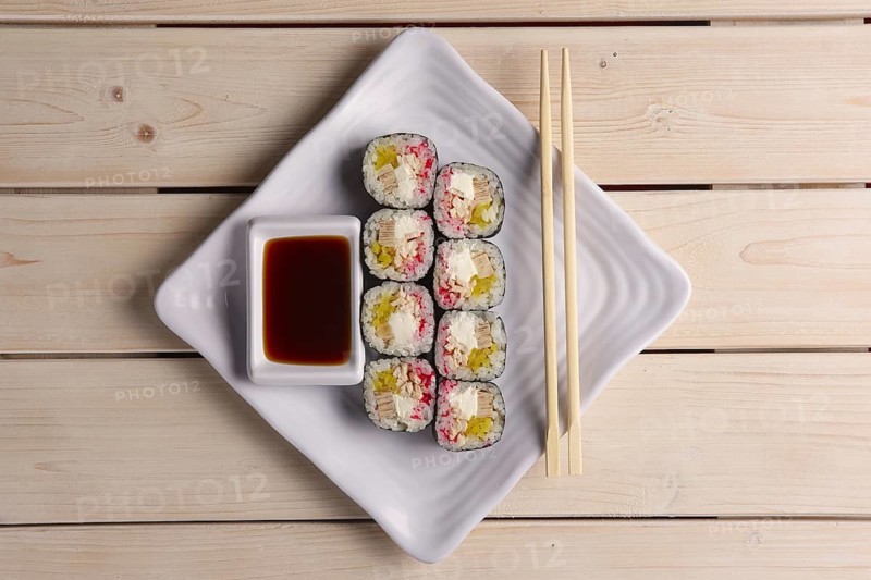 Rolls with eel and avocado on plate with soy sauce and hashi