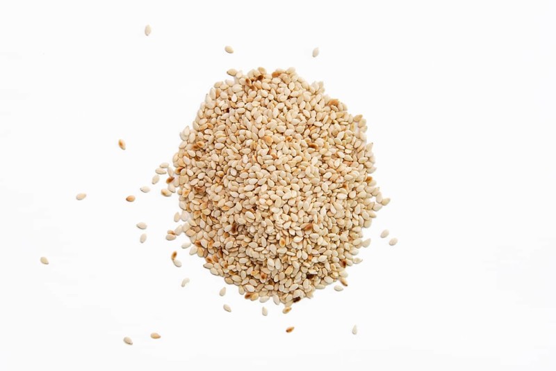 Top view of sesame seeds scattered on white paper