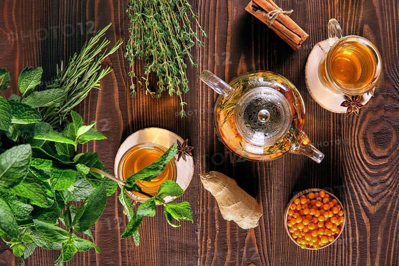 Top view of sea-buckthorn drink with thyme and cinnamon on wooden table