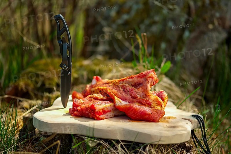 Fresh pork ribs with salt and pepper on cutting board outdoor. Selective focus photo