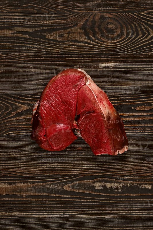 Overhead view of raw deer boneless ham over wooden background