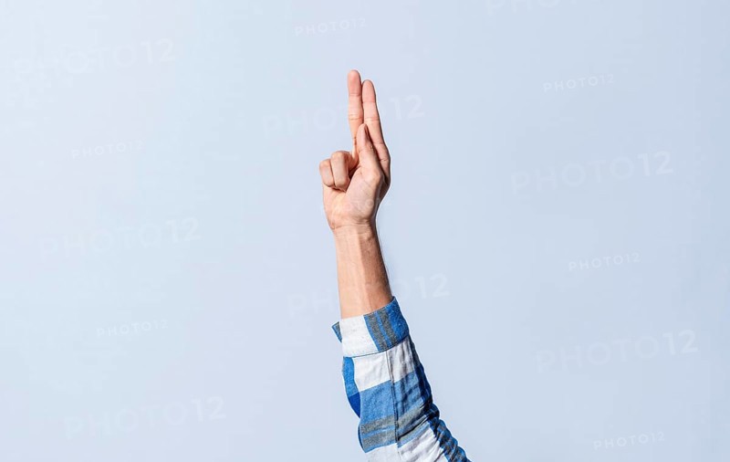 Hand gesturing the letter U in sign language on an isolated background. Man's hand gesturing the letter U of the alphabet isolated. Letter U of the alphabet in sign language