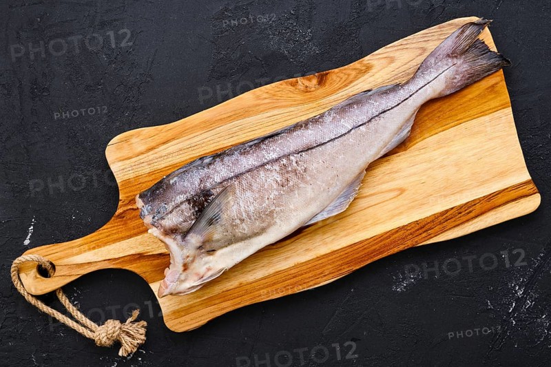 Top view of raw fresh haddock carcass on wooden cutting board