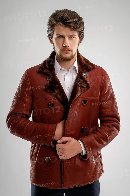 Brutal handsome unshaven man with beard and moustache in sheepskin coat with fur collar