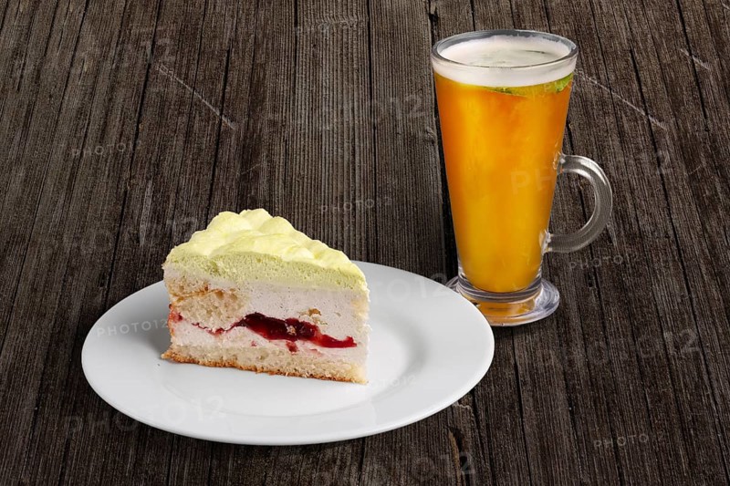 Cherry cake with whipped cream and glass of sea buckthorn tea on wooden table