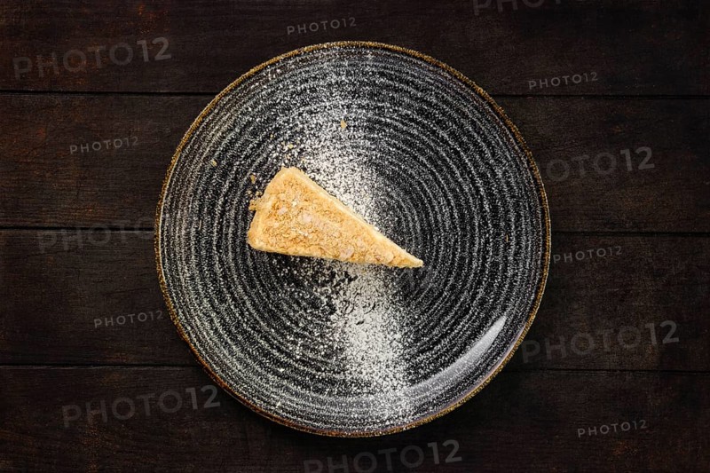Top view of plate with piece of coconut cake on wooden background