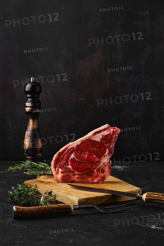 Raw strip steak bone in on dark background