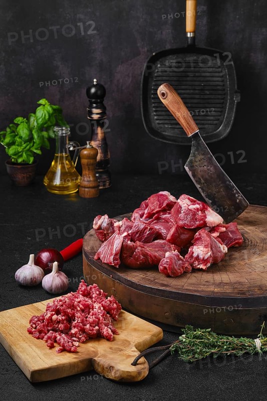 Chopping fresh beef meat for goulash or stew on wooden chopping stump