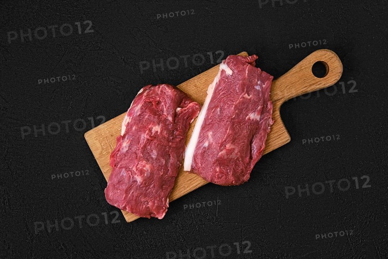 Top view of fresh lamb or veal loin steak on wooden cutting board