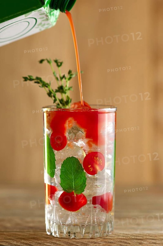 Pouring tomato juice to cocktail with vodka