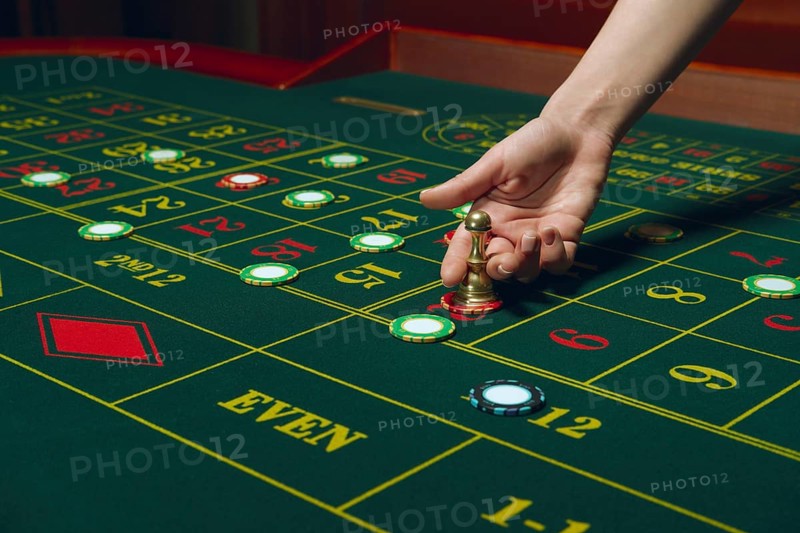 Casino roulette table with chips and cards. Winning combination. Hand of Croupier behind gambling table