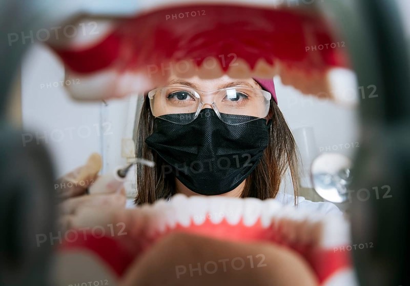 Woman dentist cleaning a mouth inside view