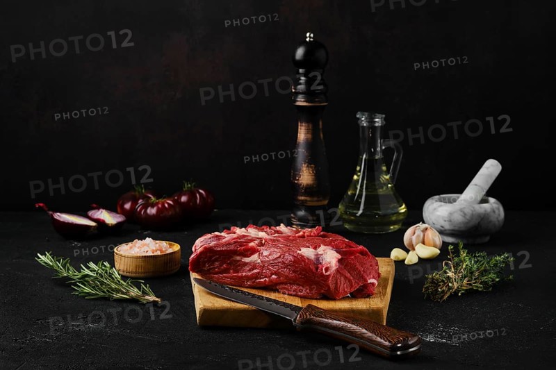 Raw beef top round roast with spices on dark background