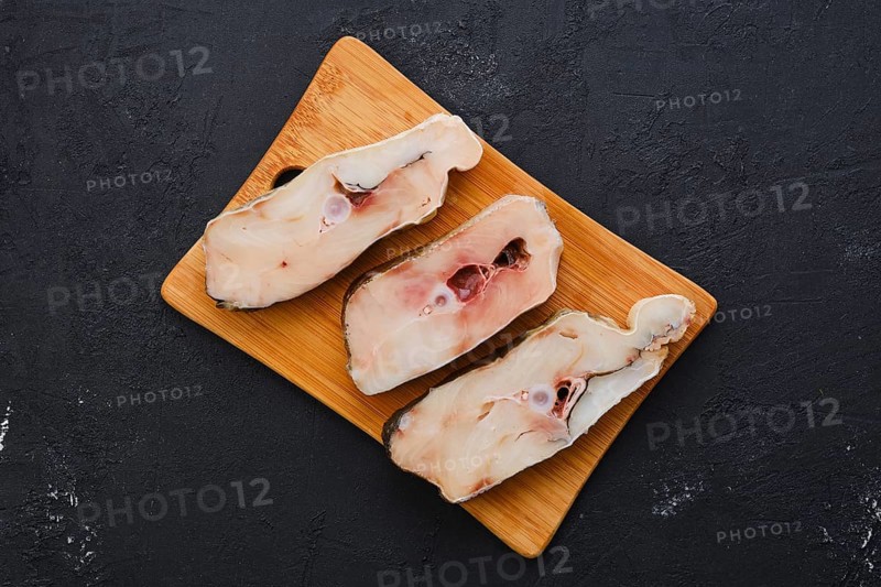 Top view of fresh raw cod steak on wooden cutting board with spice