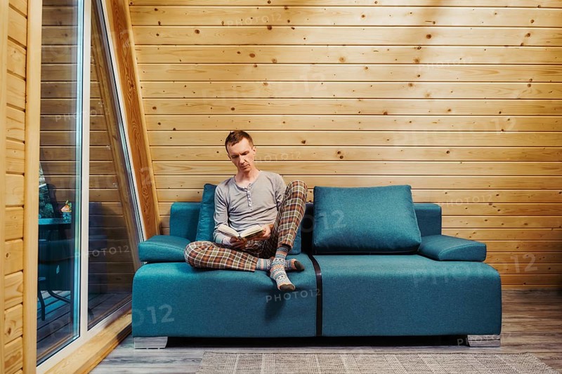 Man sits on sofa and reading a book