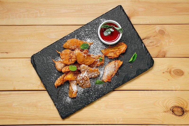 Overhead view of deep fried fruits in breading served with caramel and strawberry jam