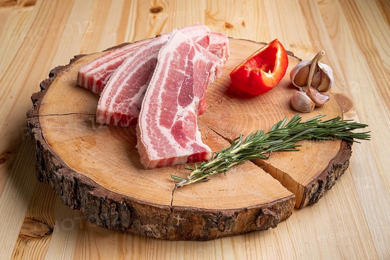 Raw fresh pork brisket slices on wooden cutting board