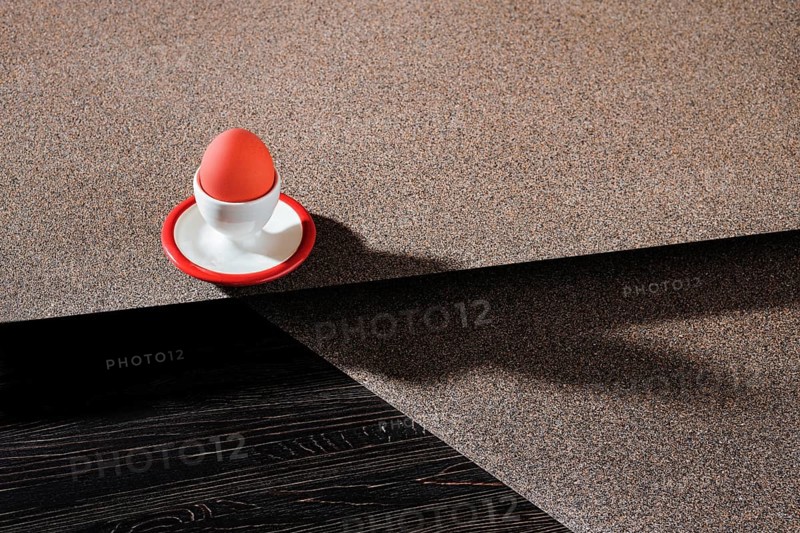 Egg cup with brown egg on abstract background and long shadow