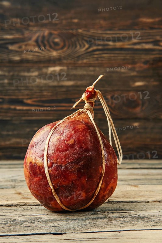 Round fermented beef sausage on wooden table
