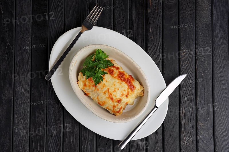 Top view of deep plate with pancakes covered with melted cheese