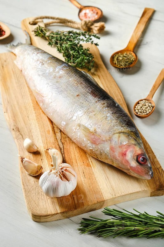 Raw frozen unpeeled omul on wooden cutting board