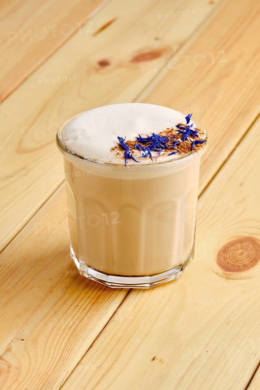 Flat white coffee in transparent glass on wooden background