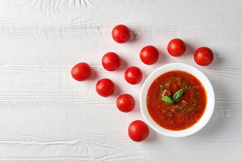 Gazpacho cold summer tomato soup with basil in a bowl on bright wooden background