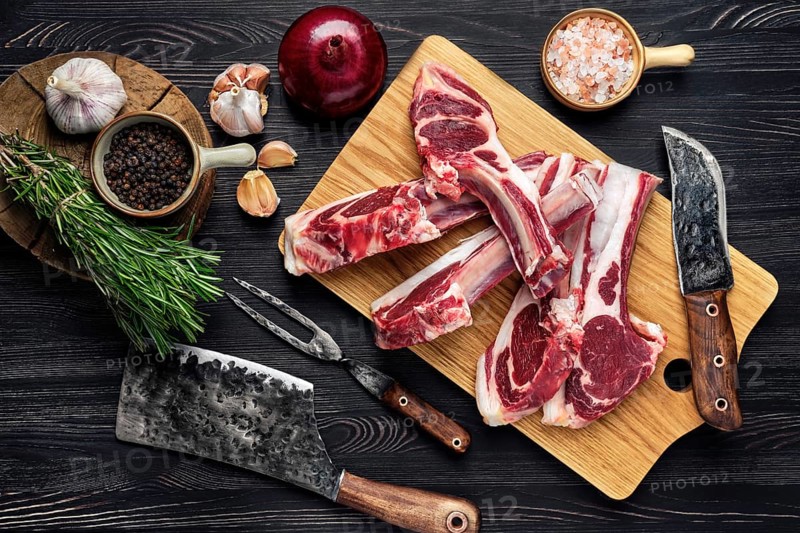 Overhead view of raw fresh lamb rack with spice on a wooden board