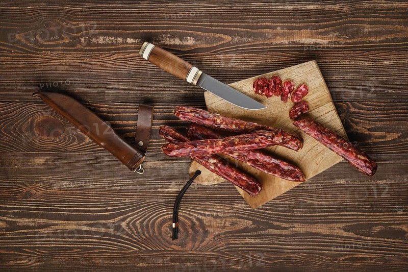 Overhead view of dried jerked deer and pork sausage on wooden background