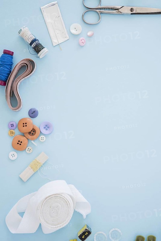 Scissor buttons needles spool measuring tape ribbon blue backdrop