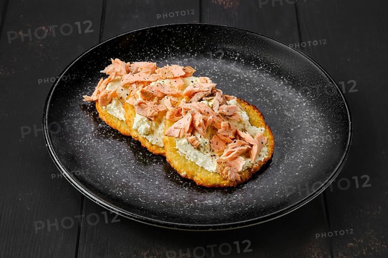 Fried potato patties with greek yogurt and salmon on a plate