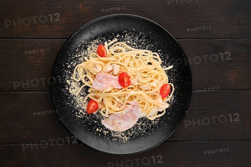Spaghetti with ham and tomatoes sprinkled with grated parmesan