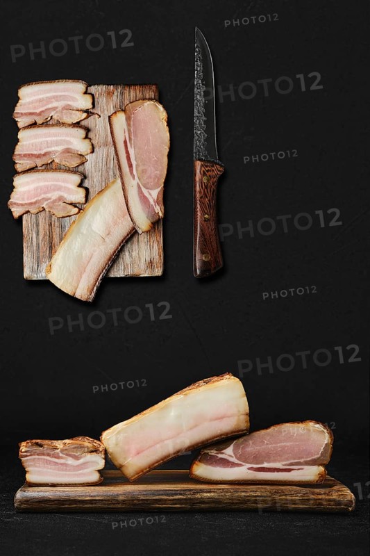 Concept for assortment of smoked pork bacon and lard on wooden cutting board