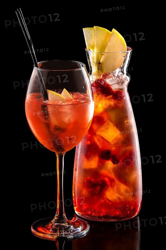 Cold sangria in pitcher and wine glass with ice cubes isolated on black background