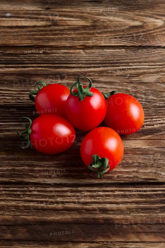 Five fresh cherry tomatoes on wooden table