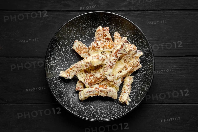Overhead view of salty bread sticks covered with melted cheese on a plate