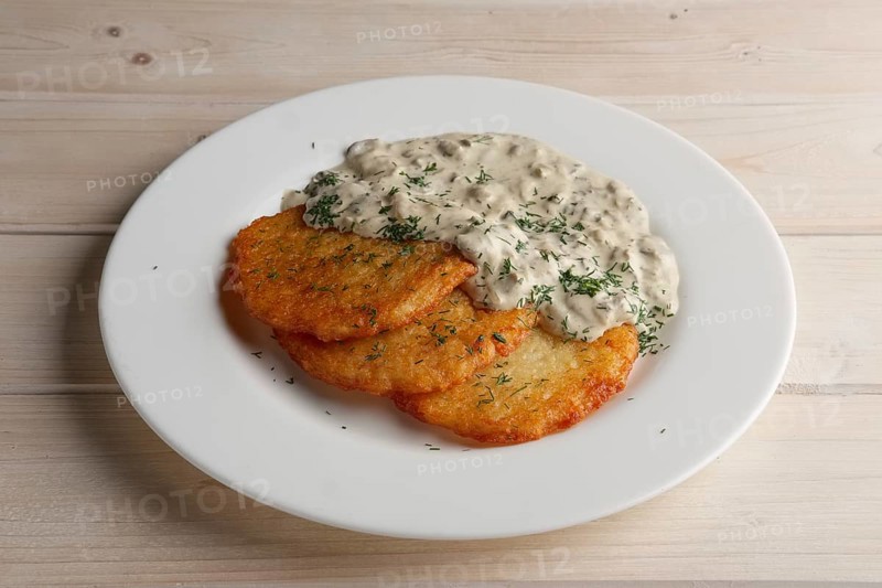 Traditional belorussian potato pancakes draniki with mushroom sauce on a plate
