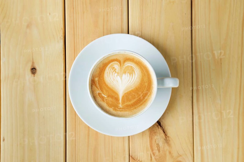 Overhead view of cappuccino in ceramic cup on wooden table