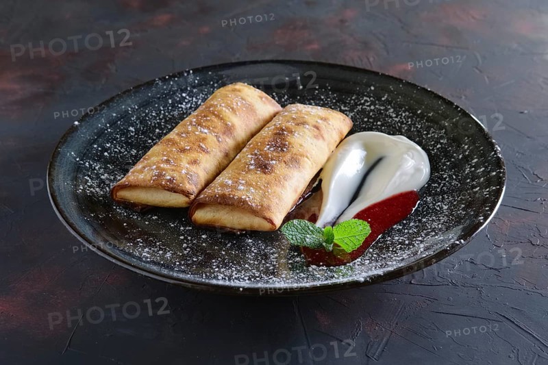 Sweet pancakes stuffed with curd and decorated with sour cream and strawberry jam